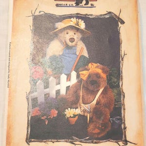 May include: A vintage-style print featuring two teddy bears in a garden setting. One bear wears a straw hat and overalls, while the other has a bow and apron. The print includes the text "Betty & Bonnie" and "Bear Sprouts Garden Club".