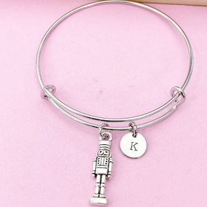 May include: Silver charm bracelet with a nutcracker charm and a silver charm with the letter K.