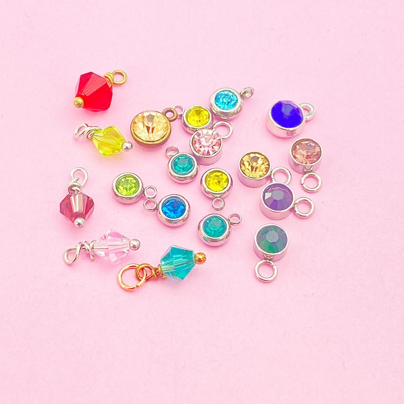 May include: Assortment of colorful rhinestone charms with silver and gold accents. The charms feature various colors including red, blue, green, yellow, pink, and clear.
