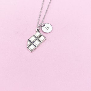 May include: Silver necklace with a chocolate bar charm and a round charm with the letter "B" on it.