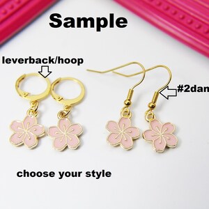 May include: Two pairs of earrings with pink flower charms. The first pair is a leverback/hoop style. The second pair is a dangle/drop style. #1 leverback/hoop #2 dangle/drop choose your style