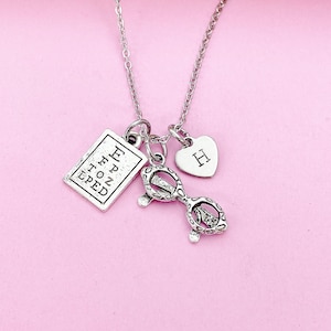 May include: Silver necklace with a heart charm, eyeglass charm, and a rectangular charm with the text "EFPZ TOZ LPED".