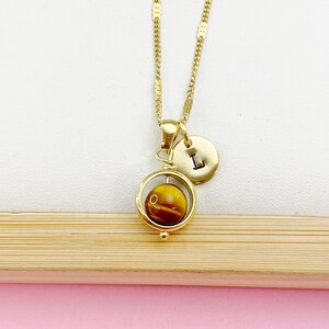 May include: Gold necklace with a spinning tiger's eye stone pendant and a gold initial charm with the letter "L".