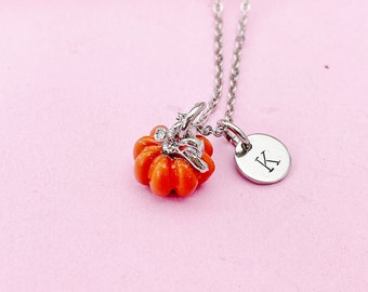May include: A silver chain necklace with a small orange pumpkin charm and a silver charm with the letter "K" on it.