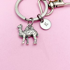 May include: Silver camel keychain with a silver keyring and a silver charm with the letter K.