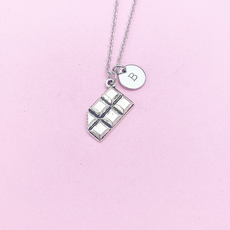 May include: Silver necklace with a chocolate bar charm and a letter 'B' charm.