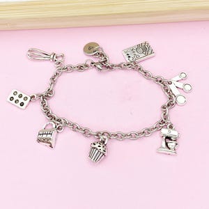 May include: A silver charm bracelet with various baking-themed charms, including a cupcake, a whisk, a measuring cup, a cookbook, a rolling pin, a mixer, and a heart charm.