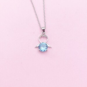May include: A silver necklace with a blue crystal pendant shaped like an angel with wings.