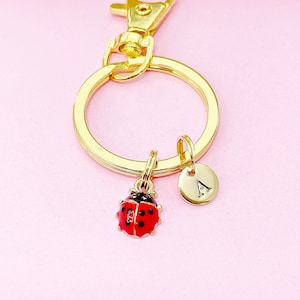 May include: Gold-toned keychain with a ladybug charm and a round charm with the letter 'A' engraved on it.