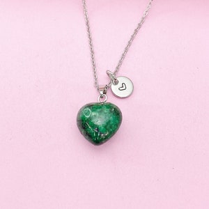May include: A silver chain necklace with a green heart-shaped pendant and a small silver charm with a heart symbol.