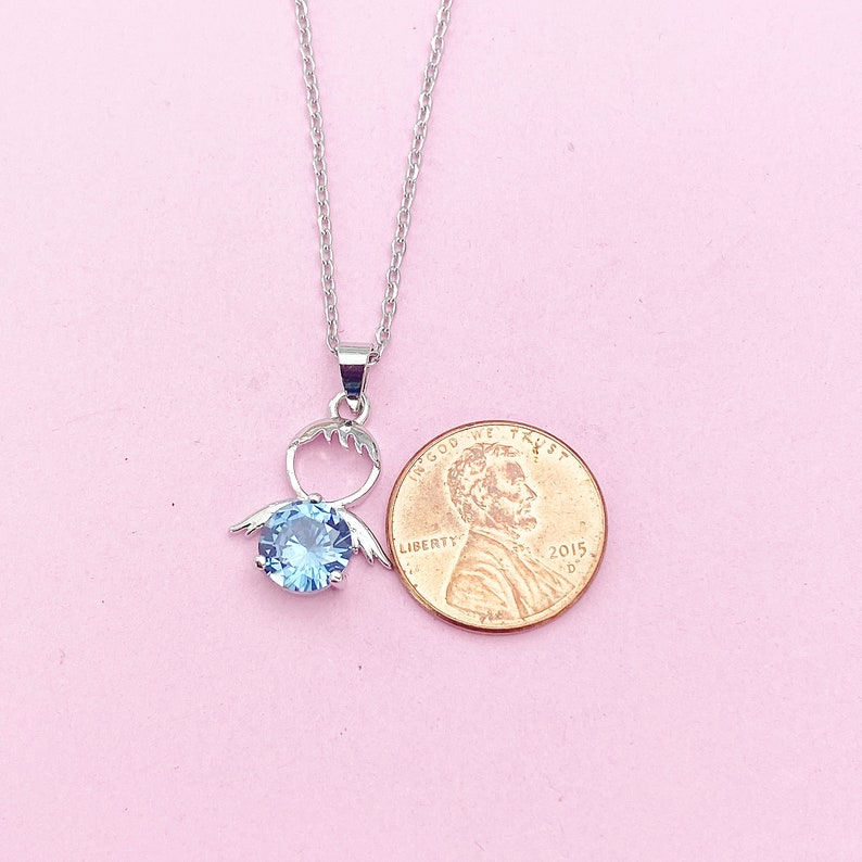 May include: A silver necklace with a pendant featuring a light blue crystal surrounded by a silver design. The pendant is about the size of a US penny.
