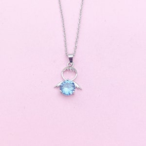May include: A silver necklace with a blue gemstone pendant shaped like a person with wings.