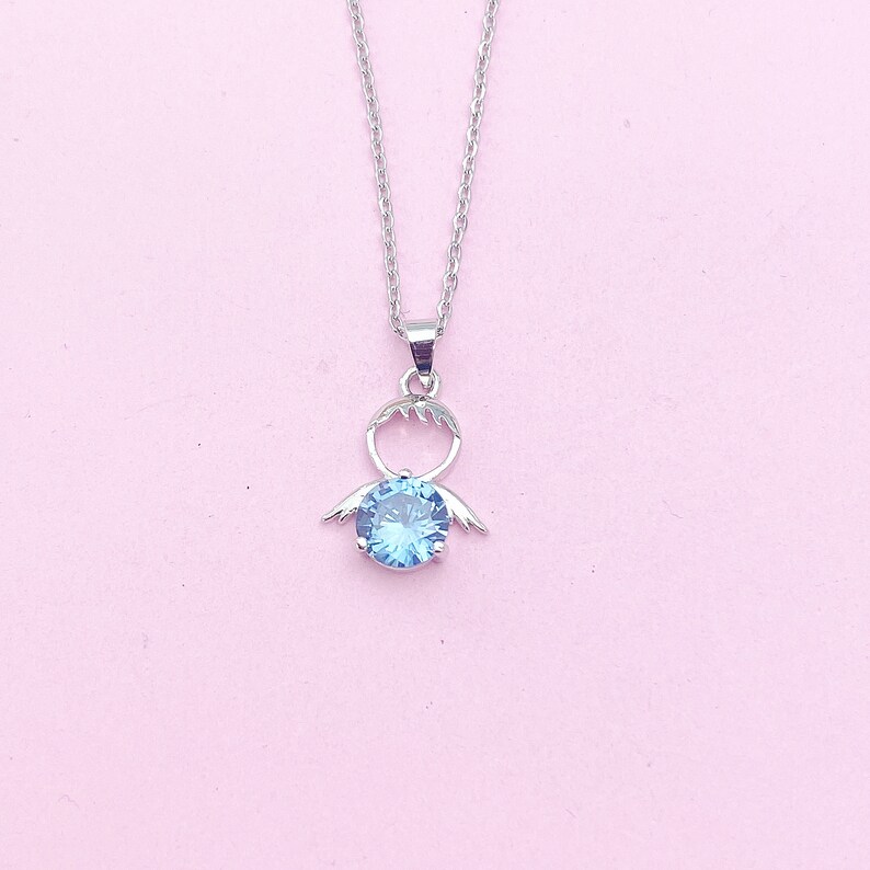 May include: A silver necklace with a blue gemstone pendant shaped like a person with wings.