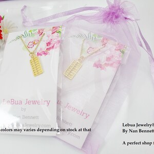 May include: Two gold abacus necklaces on white cards with floral designs. The cards have the text "LeBua Jewelry by Nan Bennett" and "Lebua Jewelry&reg;, Inc. By Nan Bennett. A perfect shop for everyone!"