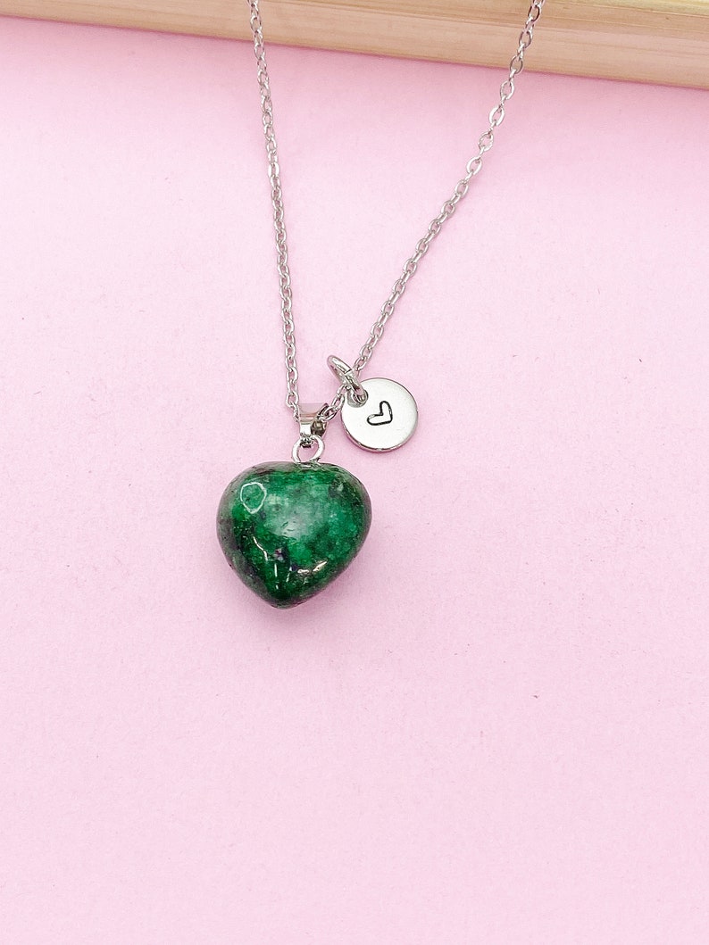 May include: A silver chain necklace with a green heart-shaped pendant and a small silver charm with a heart engraved on it.