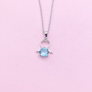 May include: A silver necklace with a blue gemstone pendant shaped like an angel with wings.