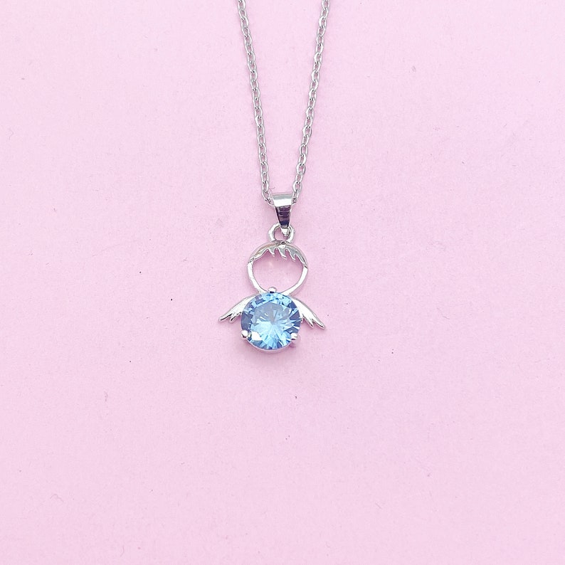 May include: A silver necklace with a blue gemstone pendant shaped like an angel with wings.