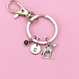 May include: Silver keychain with a wolf charm, a small charm with the letter C, and a purple crystal charm. The keychain is attached to a silver ring.