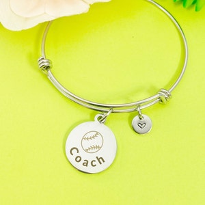 May include: Silver bangle bracelet with a charm that says "Coach" and has a softball graphic. The charm also has a small heart charm attached.