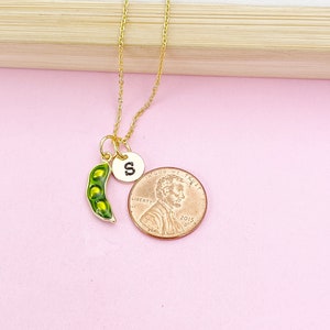 Peut inclure: Un collier dor&eacute; avec un charm en forme de cosse de pois et un petit charm rond avec la lettre "S". La cosse de pois est verte avec des pois jaunes &agrave; l'int&eacute;rieur. Une pi&egrave;ce de monnaie est &agrave; c&ocirc;t&eacute; du collier pour la comparaison de taille.