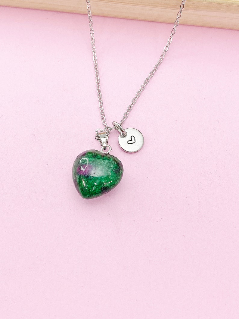 May include: A silver chain necklace with a green and pink heart-shaped pendant and a small silver charm with a heart engraved on it.