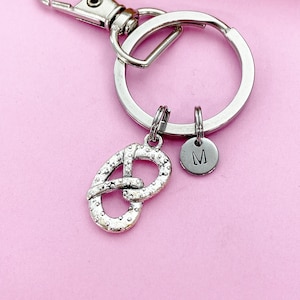 May include: Silver keychain with a pretzel charm and a small round charm with the letter "M" engraved on it.