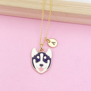 May include: A gold chain necklace with a charm of a cartoon husky dog's face and a small round charm with the letter 'A' on it.
