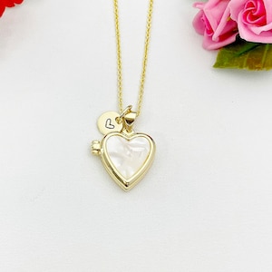 May include: A gold chain necklace with a heart-shaped locket and a small charm with a heart symbol. The locket is made of white mother-of-pearl.