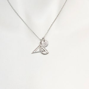 May include: A silver necklace with a silver charm of a protractor and triangle, and a silver disc charm with the letter 'N' engraved on it.
