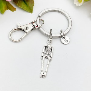 May include: Silver skeleton keychain with a silver split ring and a silver charm with the letter "W" on it.