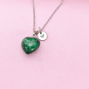 May include: A silver chain necklace with a green heart-shaped pendant and a small silver charm with a heart engraved on it.