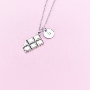 May include: Silver necklace with a chocolate bar charm and a round charm with the letter "B" engraved on it.