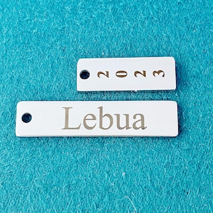 May include: Two white rectangular tags with rounded corners. The top tag has the year 2023 printed in gold. The bottom tag has the word "Lebua" printed in gold.