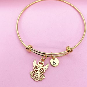 K&ouml;nnte beinhalten: Goldenes Armreif-Armband mit einem Engelsanh&auml;nger und einem kleinen Anh&auml;nger mit dem Buchstaben K.