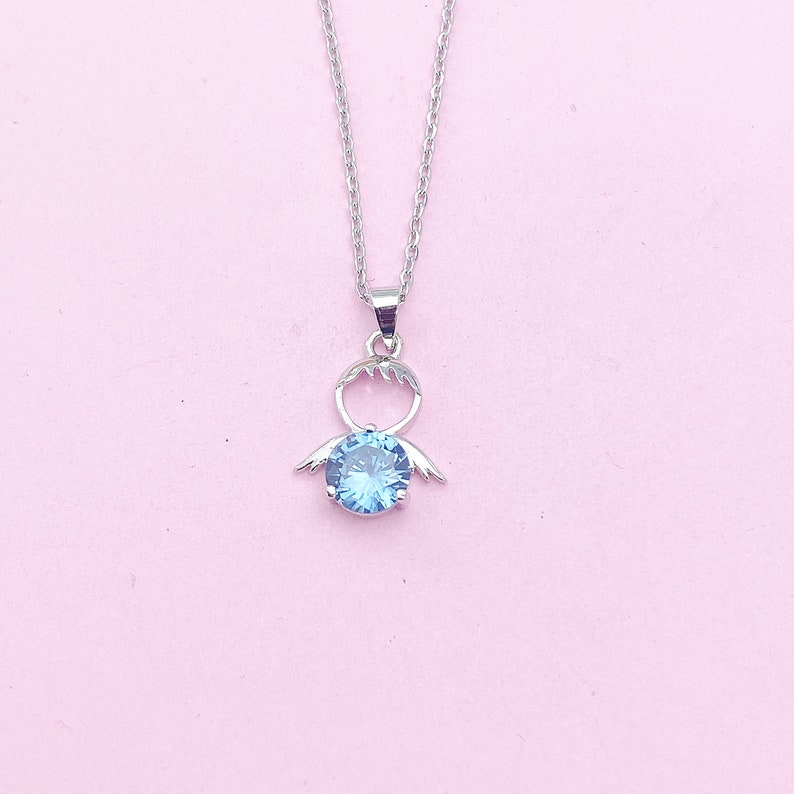 May include: A silver necklace with a blue gemstone pendant shaped like a stylized angel with wings.