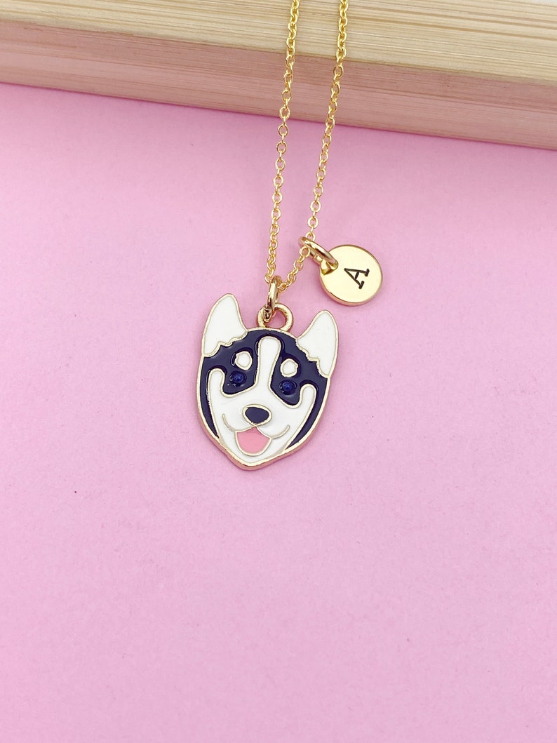 May include: A gold chain necklace with a black and white husky dog charm and a gold initial charm with the letter "A".
