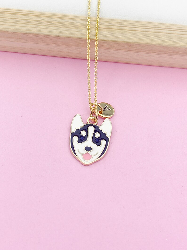 May include: Gold chain necklace with a black and white husky charm and a gold initial charm. The initial charm is a letter A.