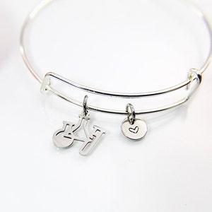 May include: A silver bangle bracelet with two charms. One charm is a heart and the other is a silhouette of a chemistry beaker and flask.