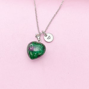 May include: A silver chain necklace with a green heart-shaped pendant and a small silver charm with a heart engraved on it.