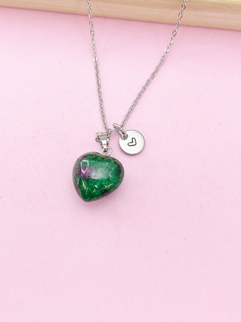 May include: A silver chain necklace with a green heart-shaped pendant and a small silver charm with a heart engraved on it.