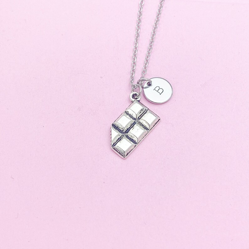 May include: A silver necklace with a chocolate bar charm and a silver disc charm with the letter "B" on it.