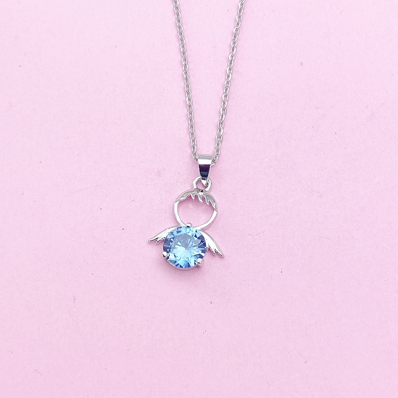 May include: A silver necklace with a blue crystal pendant shaped like a stylized angel with wings.