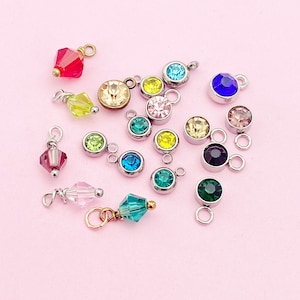 May include: Assortment of colorful crystal charms with various shapes and sizes. The charms are made of glass and metal and are perfect for jewelry making.