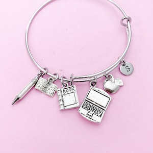 May include: Silver charm bracelet with charms of a pencil, book, laptop, apple, and a letter 'S'.