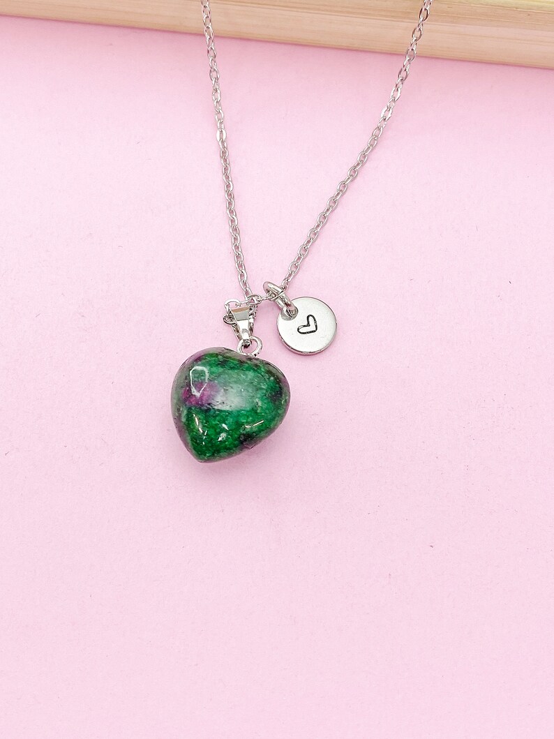 May include: A silver chain necklace with a green and pink heart-shaped pendant and a small silver charm with a heart engraved on it.
