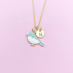 May include: A gold necklace with a blue and white bird charm and a gold disc charm with the letter 'H' engraved on it.