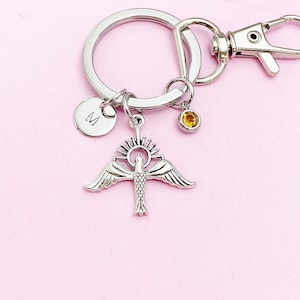 May include: Silver keychain with a bird and sun charm, a small round charm with the letter 'M' and a small amber-colored crystal charm.