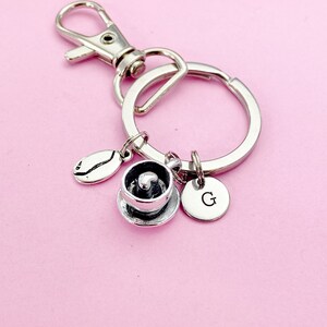 May include: Silver keychain with a coffee cup charm, a coffee bean charm, and a charm with the letter G.