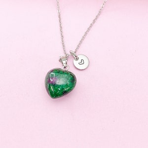 May include: A silver chain necklace with a green heart-shaped pendant and a small silver charm with a heart engraved on it.
