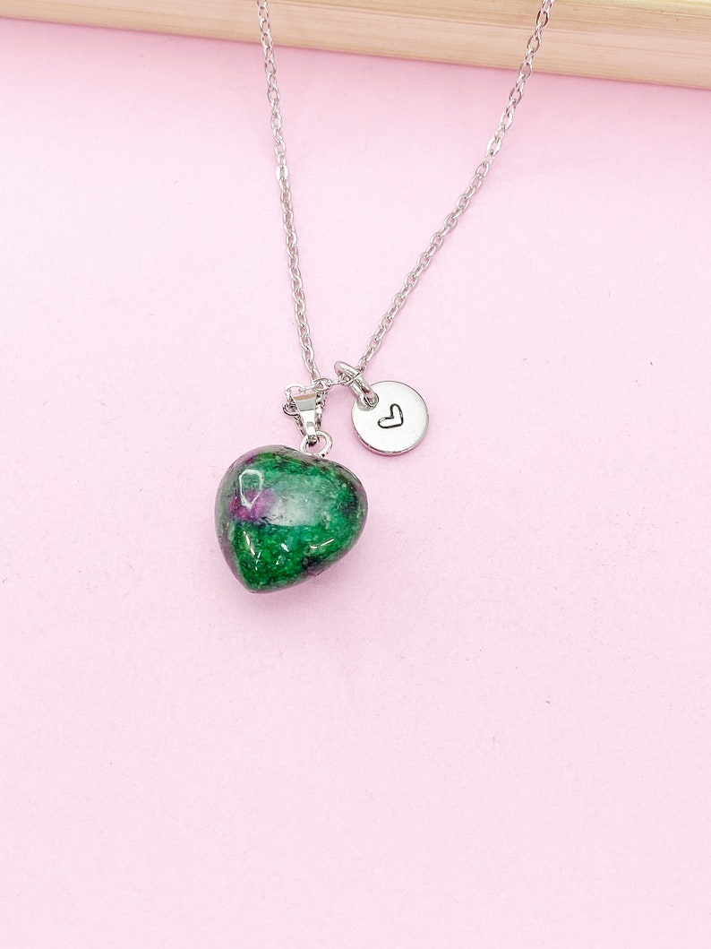 May include: A silver chain necklace with a green heart-shaped pendant and a small silver charm with a heart engraved on it.